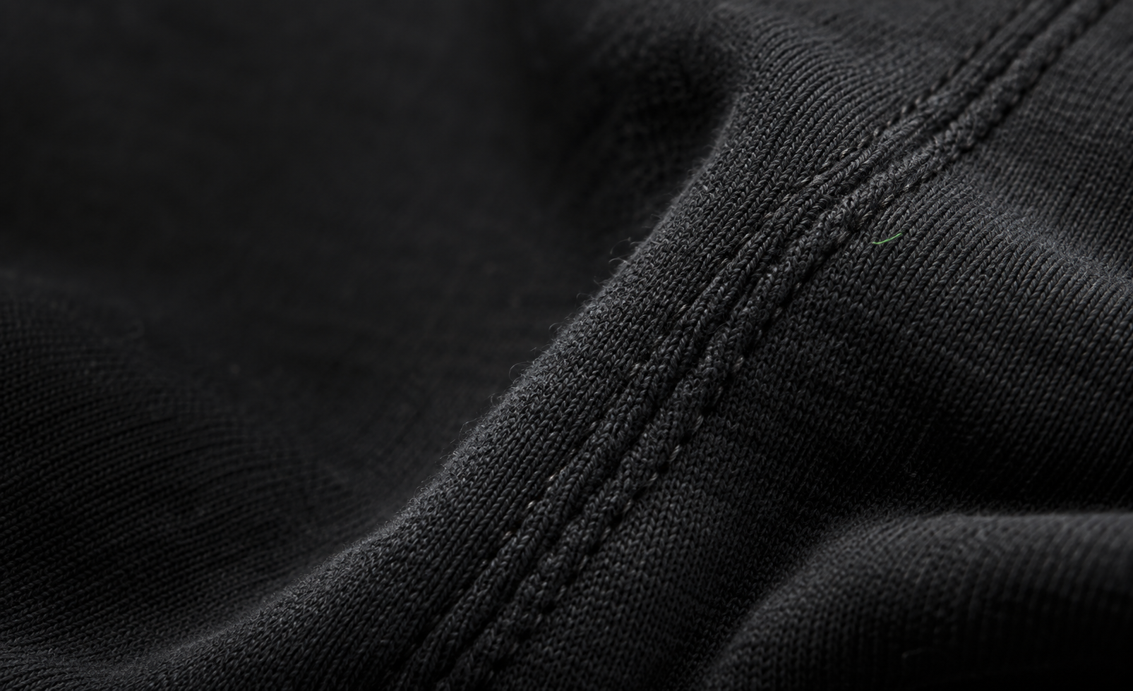 Editorial close-up of dark fabric and a green printed detail
